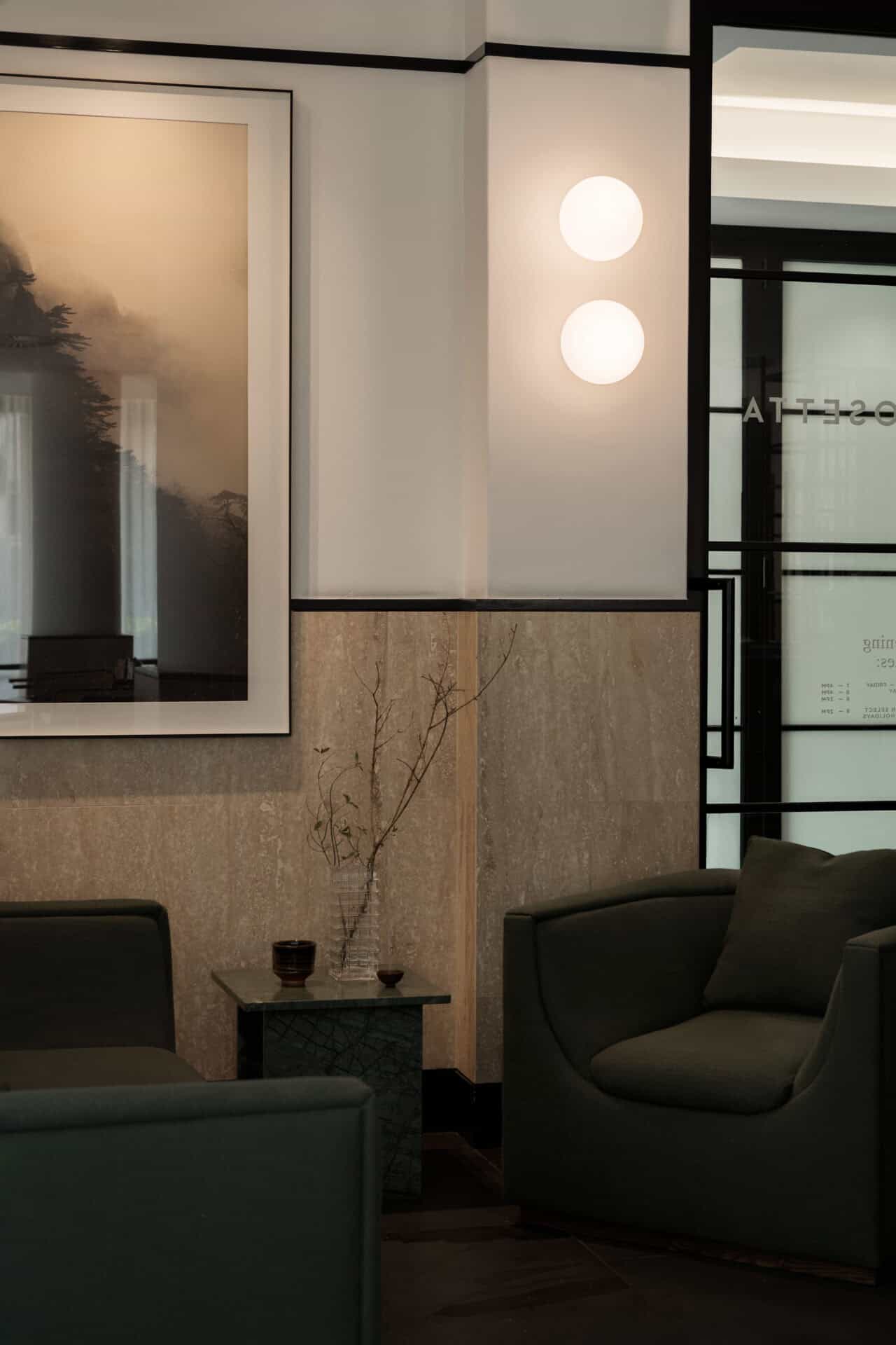 Artwork and globe lights above a green armchair at Rosetta Roastery
