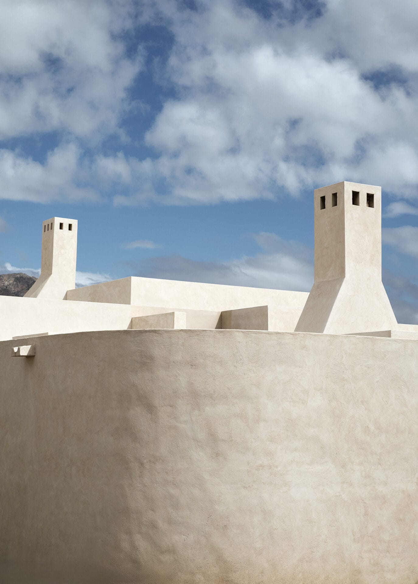 Rendered chimneys and parapet roofline at Mura against an open sky