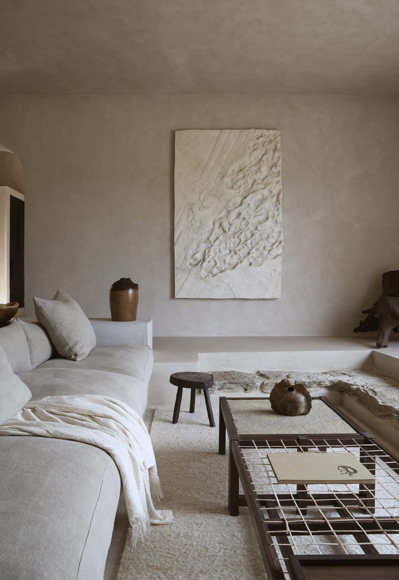 Seating area at Mura with a textured relief artwork above a low linen sofa