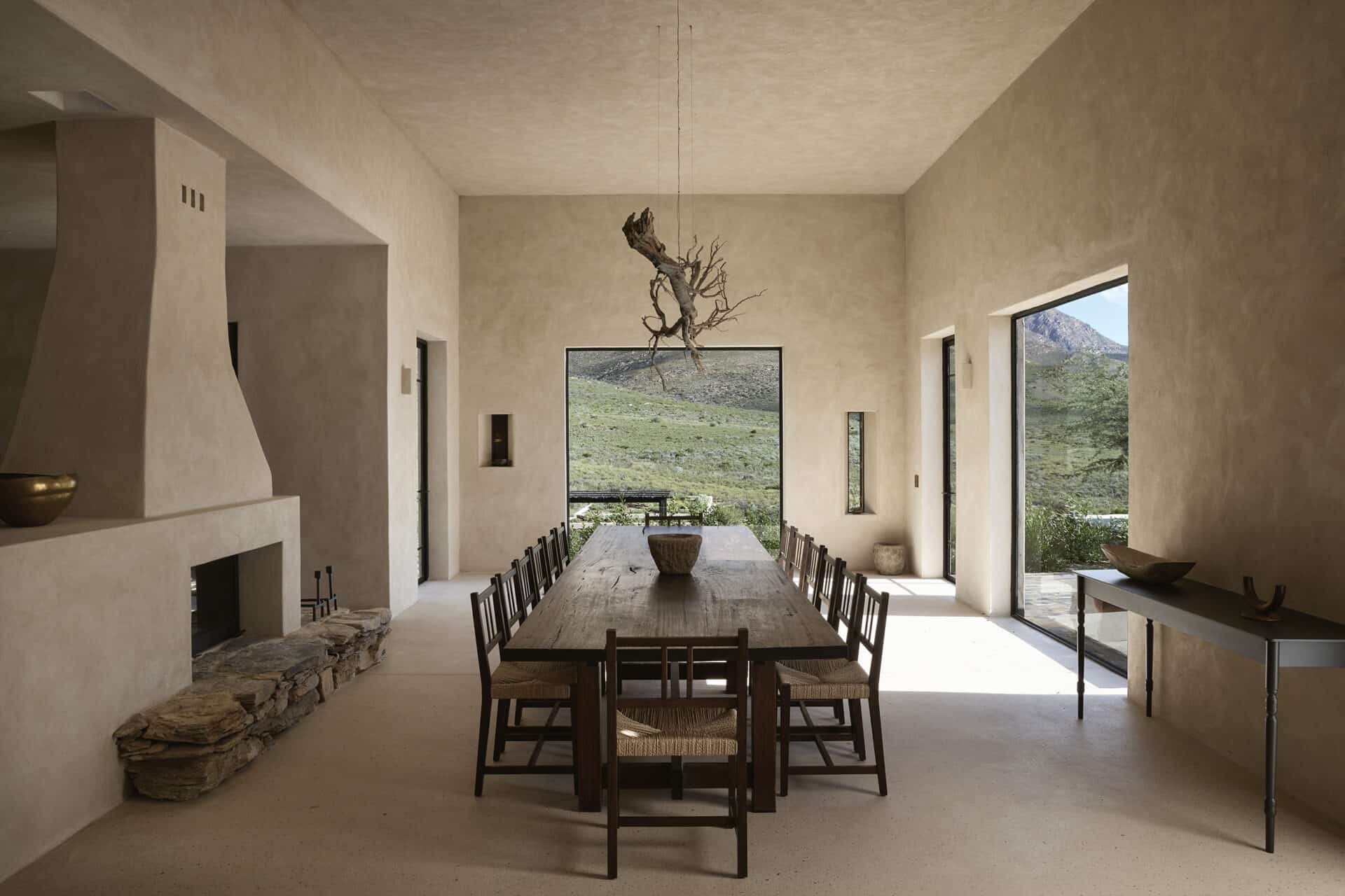 Dining room at Mura with a long timber table, rush-seated chairs and a sculptural driftwood light