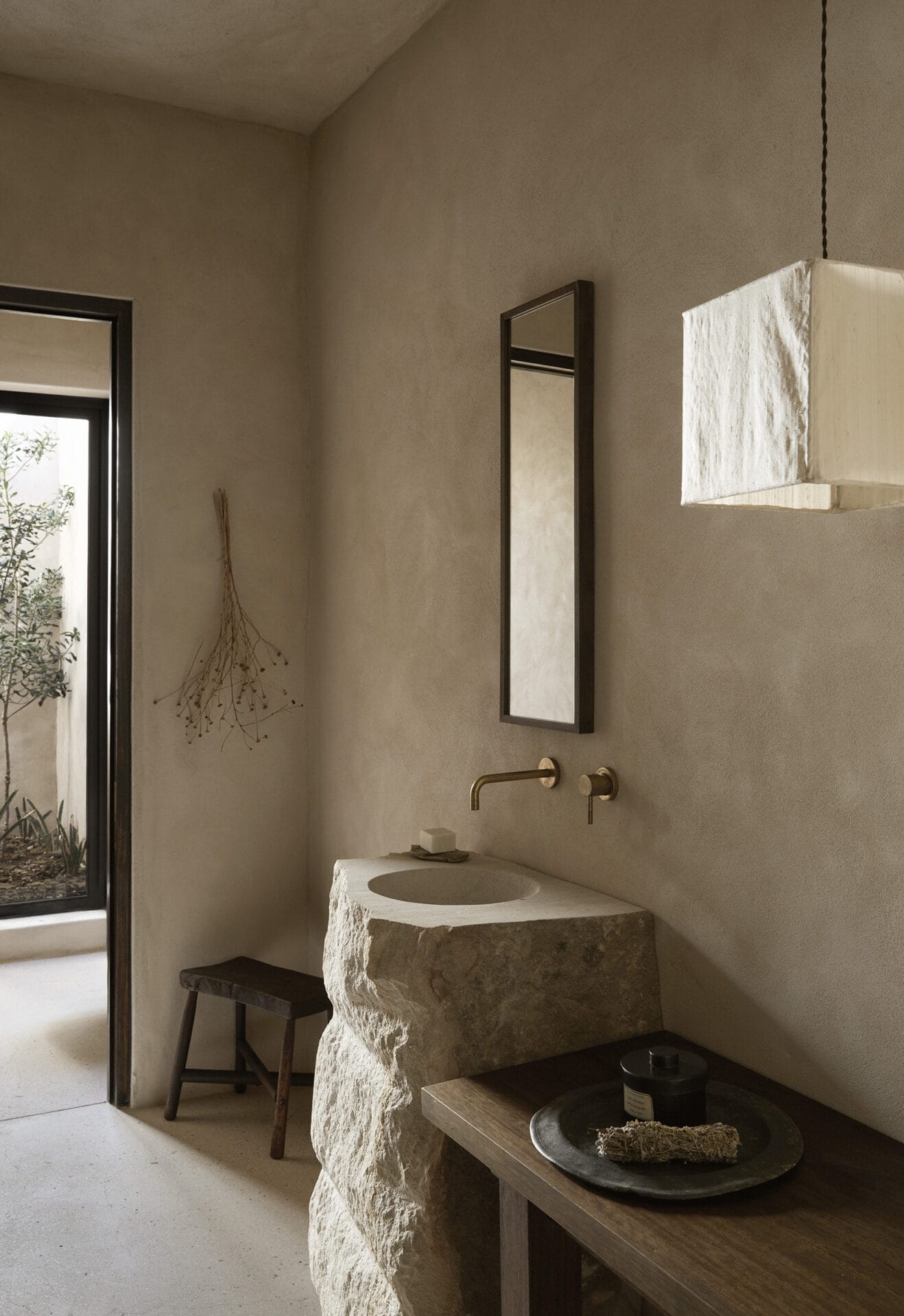 Bathroom at Mura with a carved stone basin and wall-mounted brass tapware