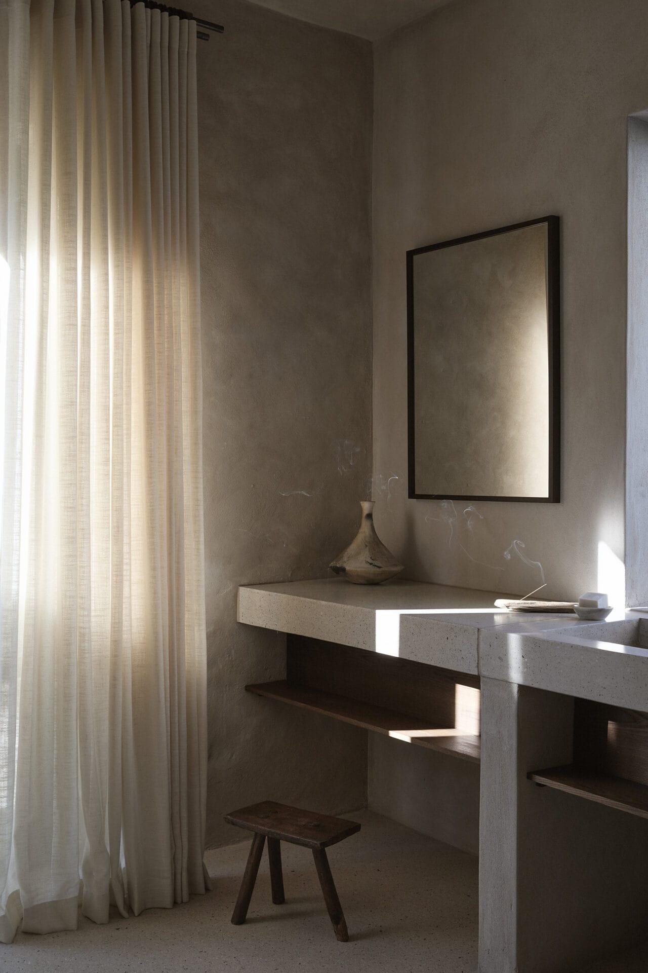 Twin plaster basins at Mura behind a floor-length linen curtain