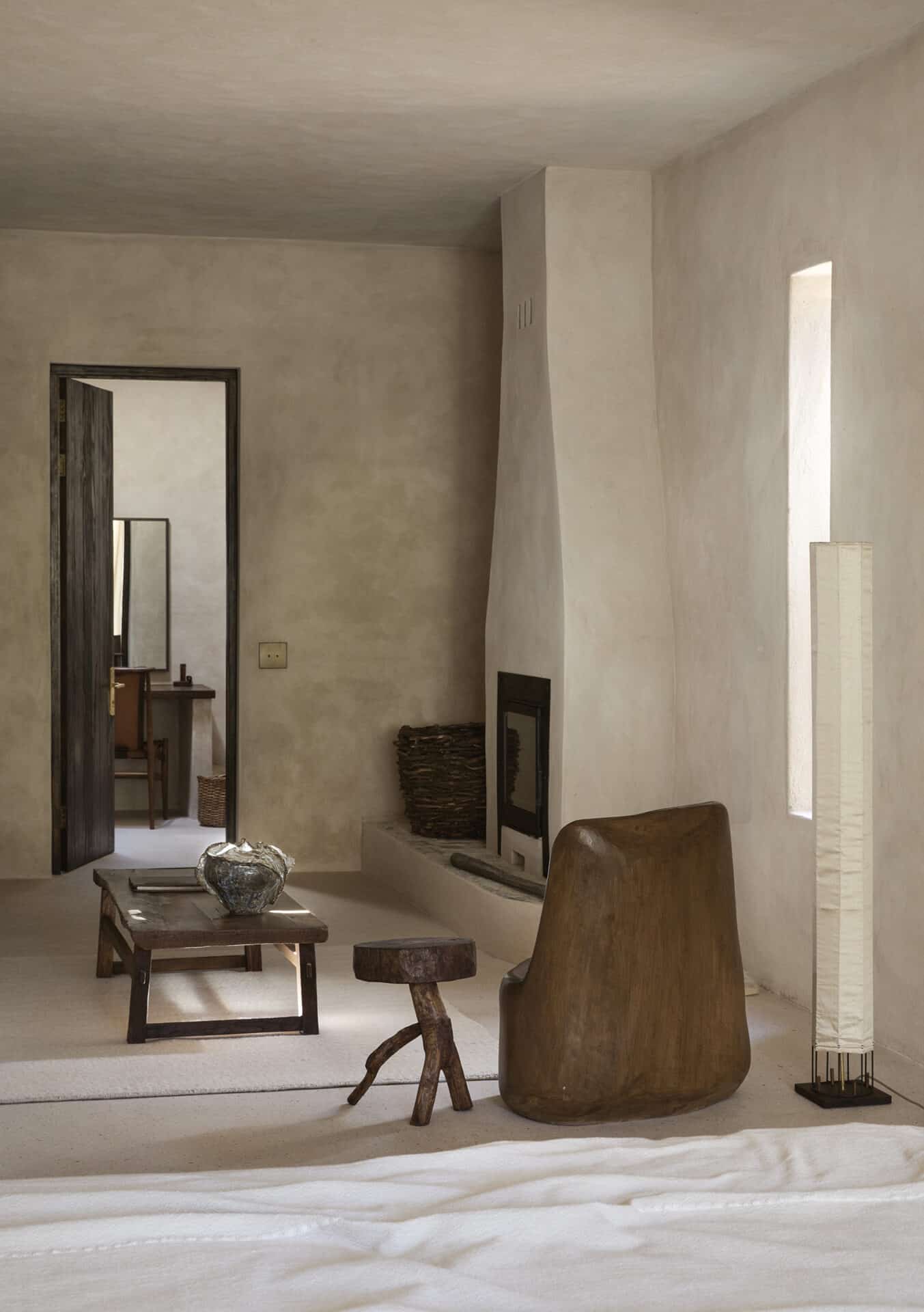 Bedroom at Mura with a corner fireplace and a sculptural timber chair