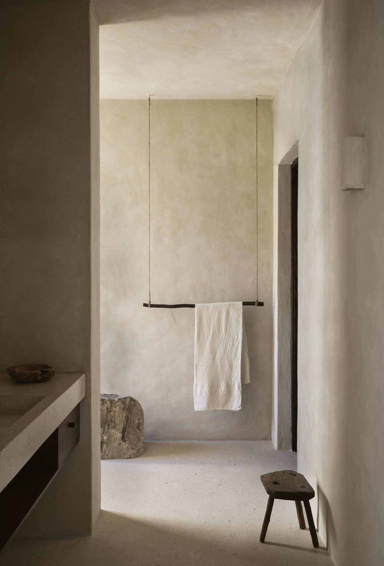 Plastered passage at Mura with a timber towel rail and low stool