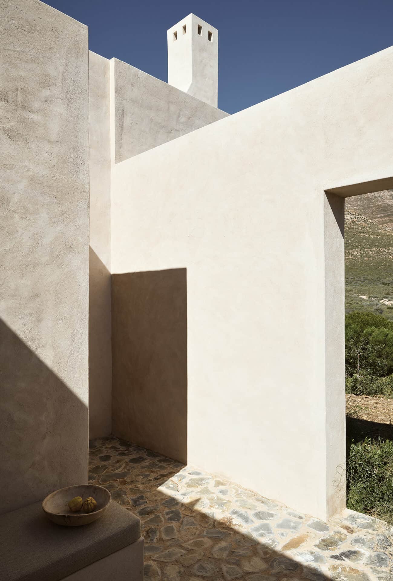 Rendered exterior volumes and chimney at Mura above a pebbled courtyard