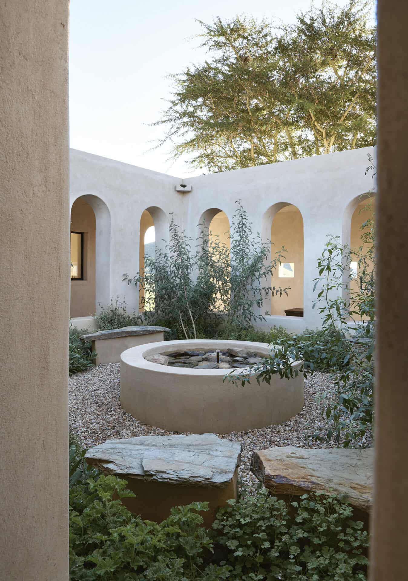 Arched courtyard at Mura enclosing a circular stone fire pit
