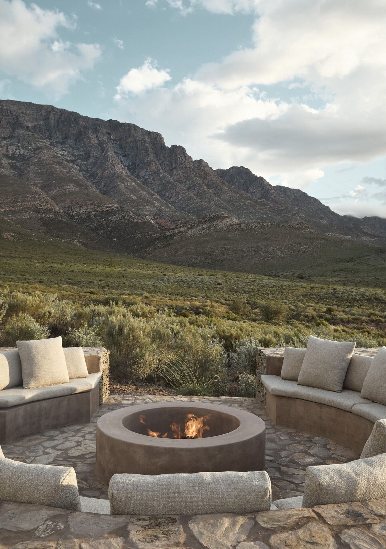 Sunken fire pit with curved seating at Mura, facing the mountains