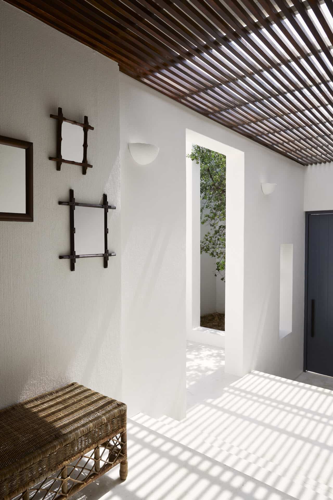 Entrance hall at House T with a slatted timber ceiling and woven bench