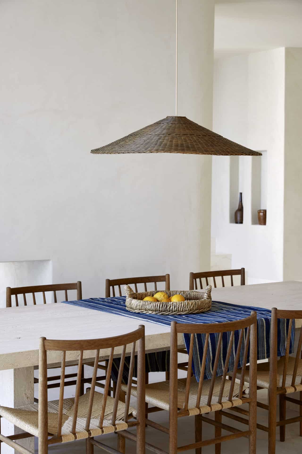 Dining table at House T laid with a blue runner beneath a woven pendant