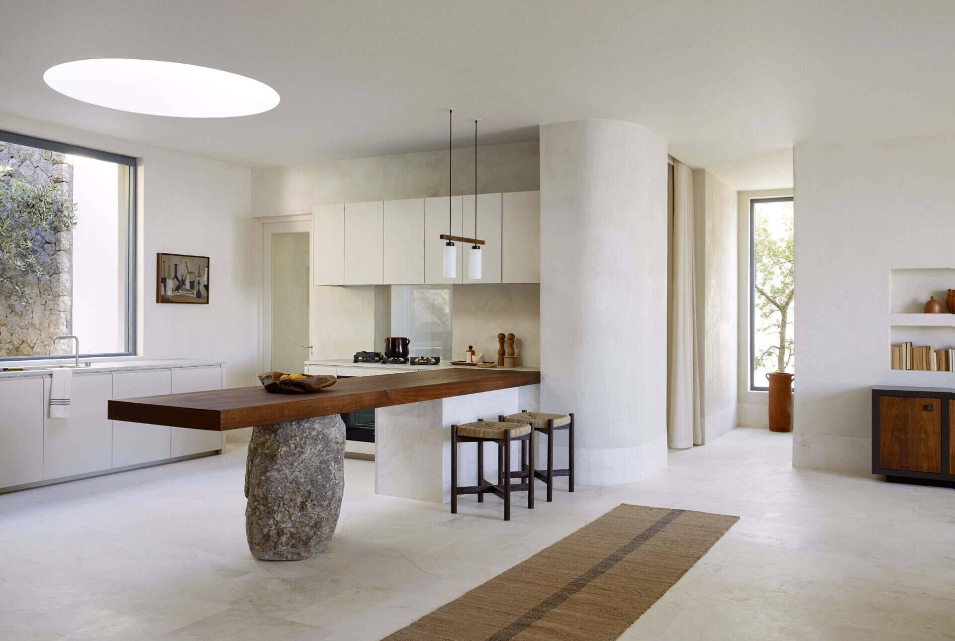 Kitchen at House T with a timber island on a boulder base below a circular skylight