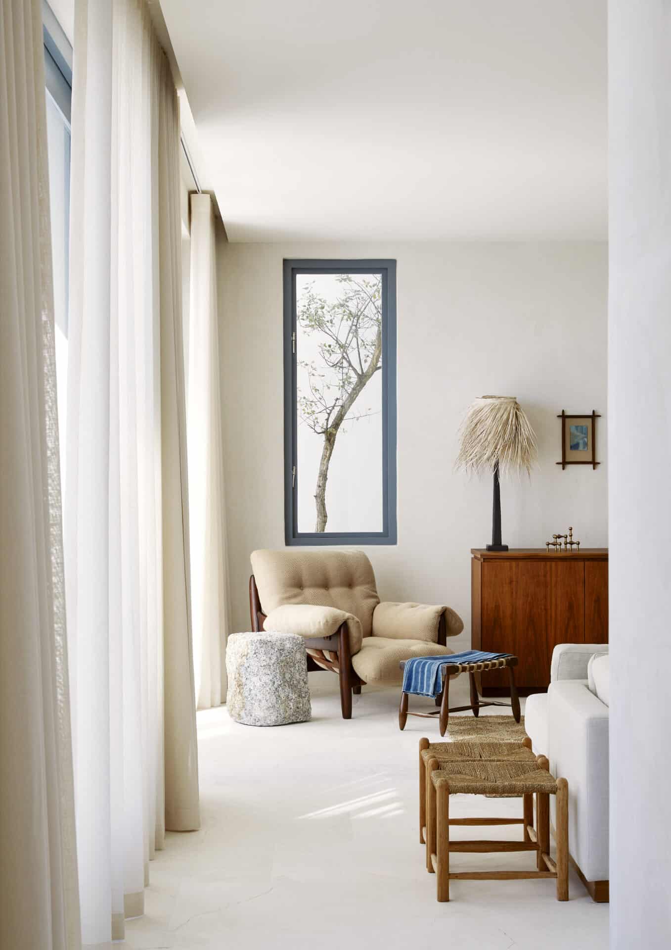 Quiet sitting room at House T with a mirrored reveal and woven stools