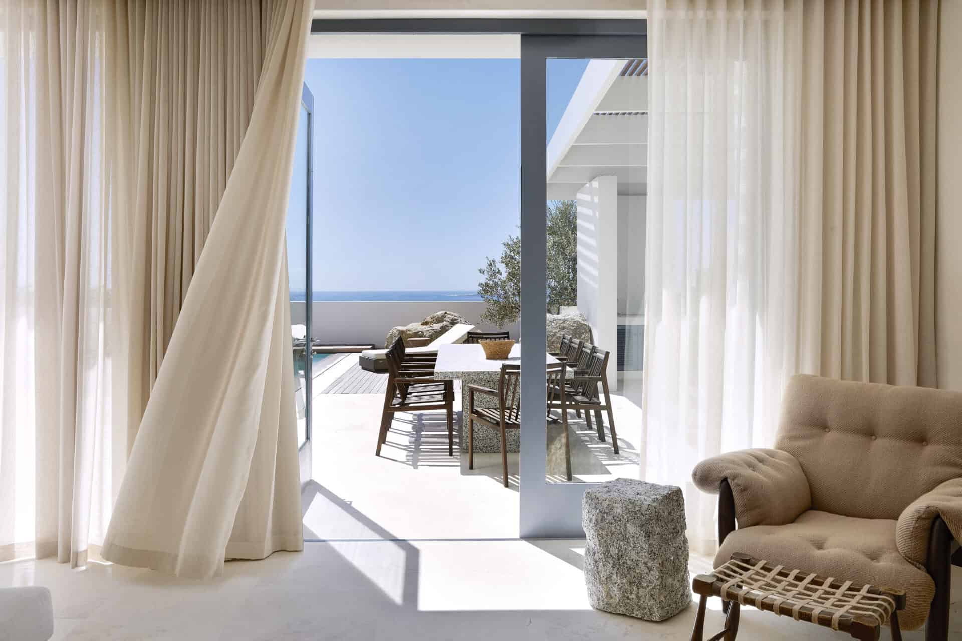 Curtained doors at House T opening onto a sea-facing terrace