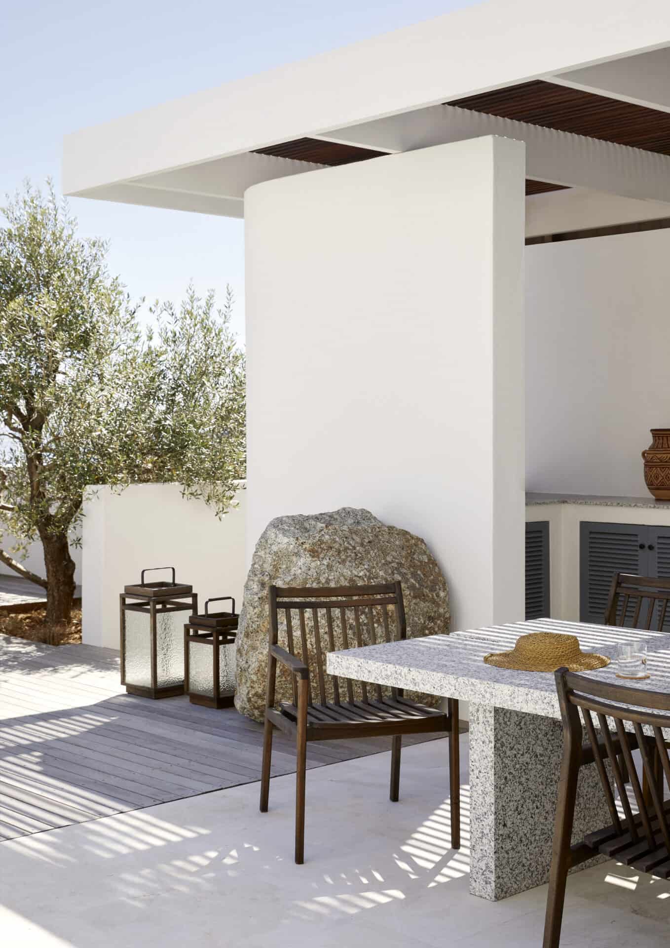 Shaded outdoor dining at House T beneath a timber pergola and olive tree
