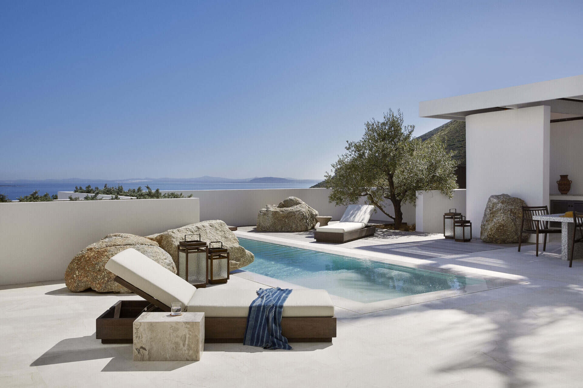 Pool terrace at House T above the Atlantic, with olive trees and stone seating
