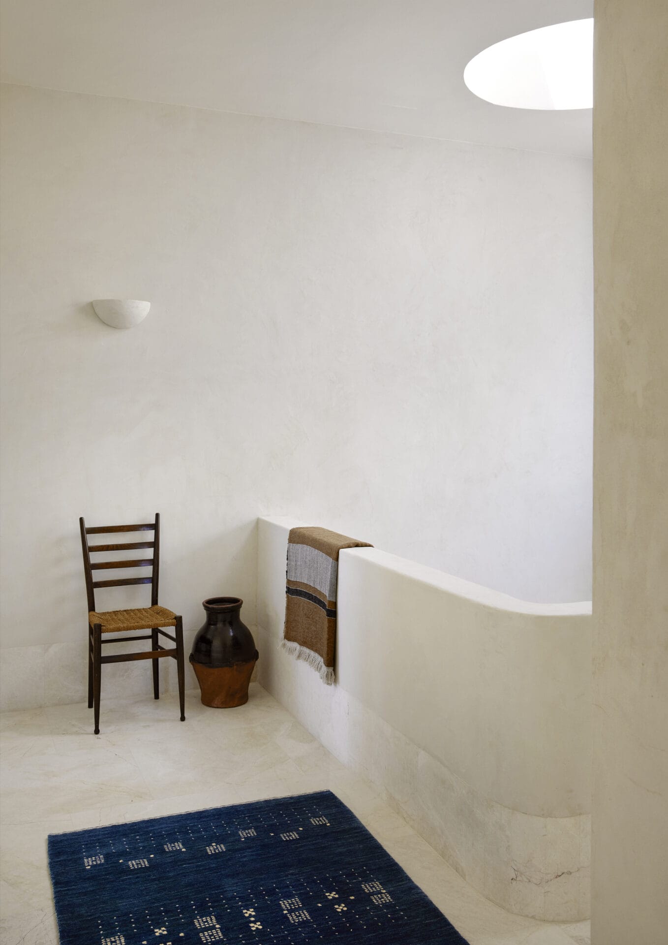 Curved plaster hallway at House T with an antique chair and a kilim runner