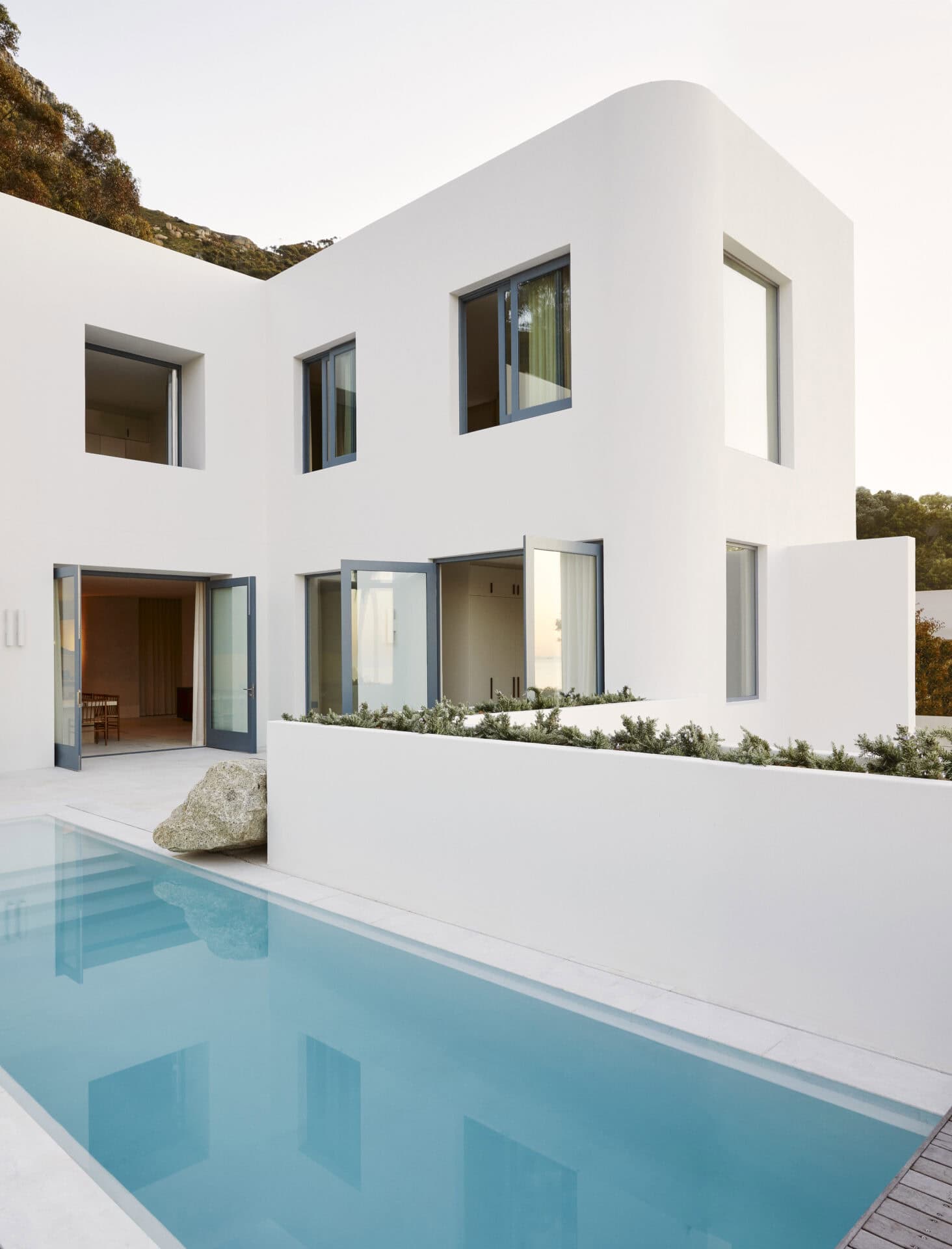 Pool and white rendered volumes at House T, set into the mountainside